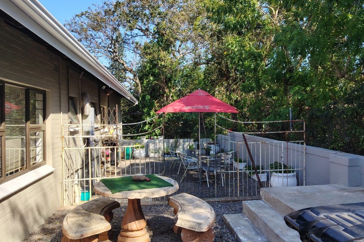 Rear exterior area featuring a concrete patio, perimeter wall, and metal security fencing, providing a functional outdoor space.