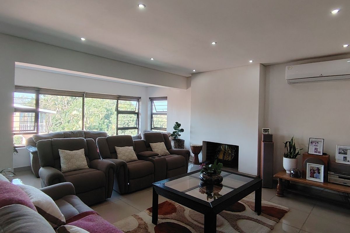 Spacious living room featuring a built-in fireplace, tiled flooring, recessed lighting, and a split-system air conditioner, with large windows providing natural light.