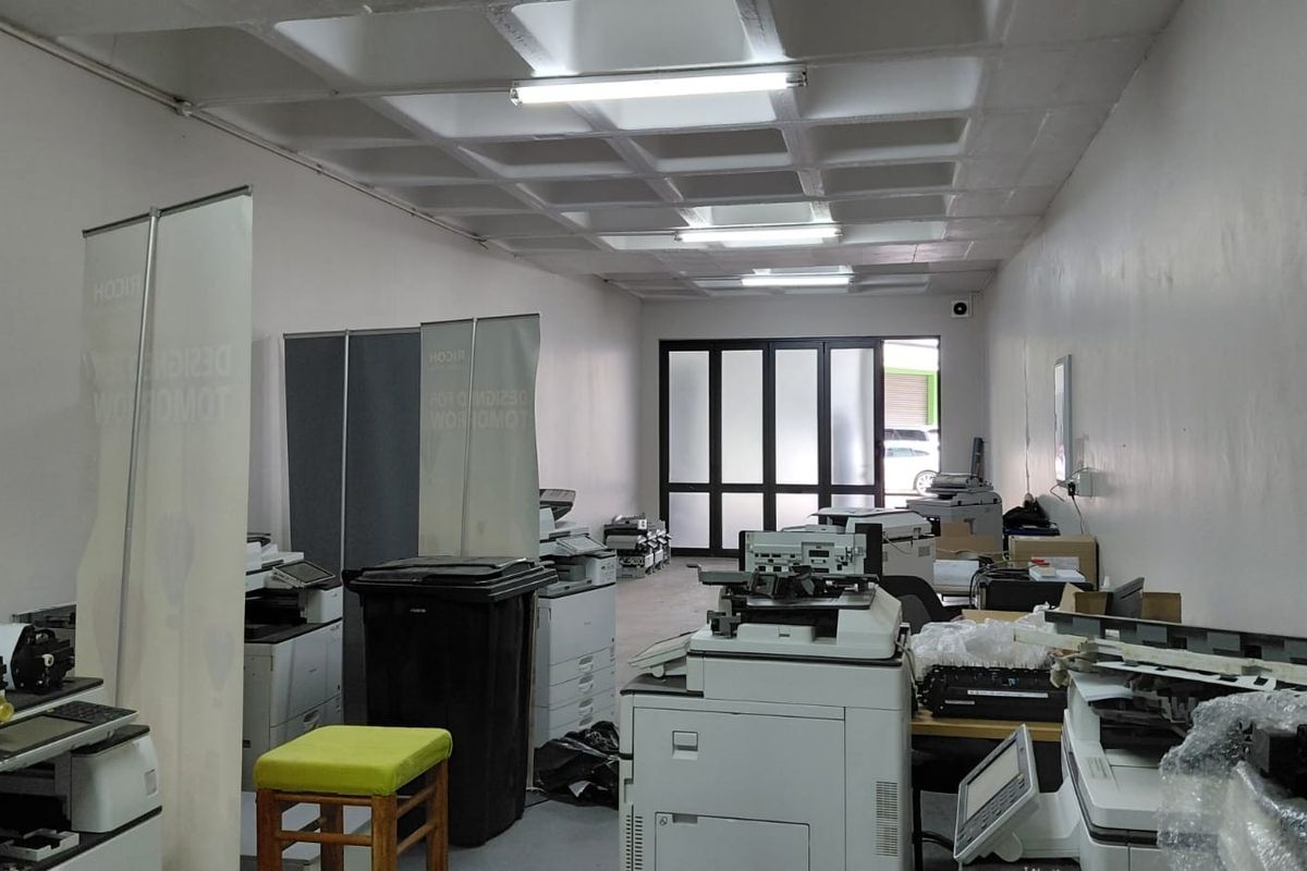 Industrial office space featuring a waffle slab ceiling, fluorescent lighting, and a glass panelled entrance door.