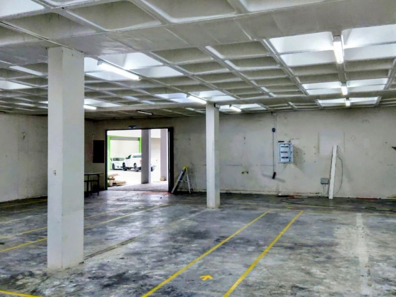 Spacious industrial utility area featuring a waffle slab ceiling, concrete flooring with painted markings, and structural support columns.