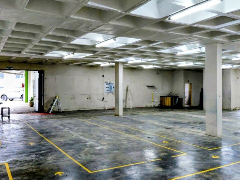 Spacious industrial utility area featuring a waffle slab ceiling, concrete flooring with floor markings, and structural support columns, suitable for various commercial or storage uses.