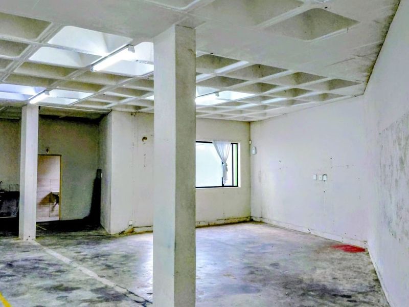 Spacious industrial open-plan area featuring a distinctive waffle slab ceiling, concrete flooring, and structural columns, suitable for versatile commercial or workshop use.