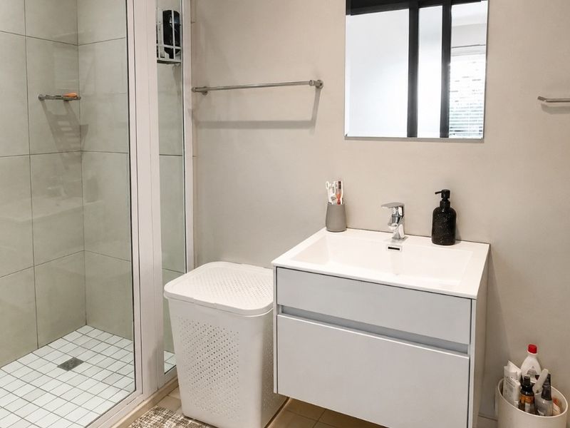 Modern bathroom featuring a glass-enclosed shower, a sleek wall-mounted vanity with a basin, and contemporary fixtures.