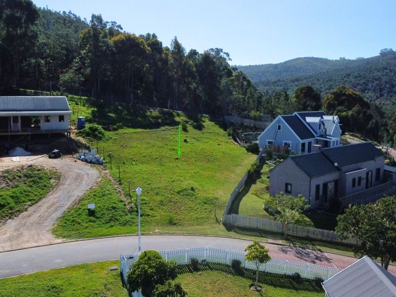 Aerial view of a vacant residential plot situated in a developed estate, featuring surrounding greenery and established neighboring homes.