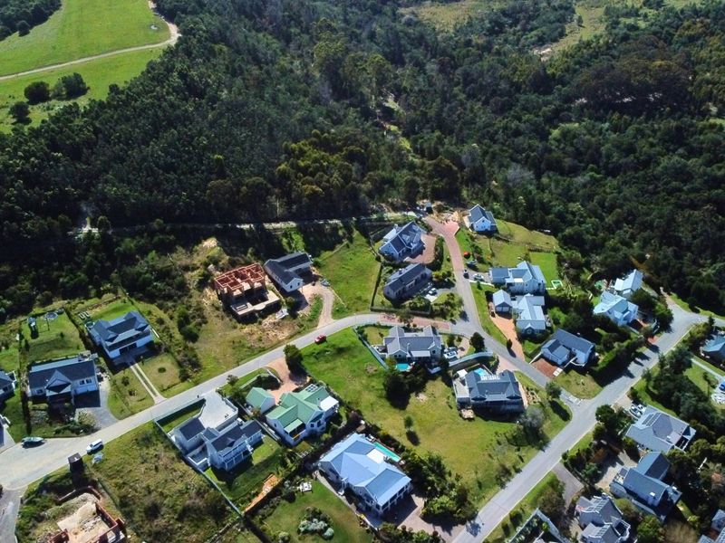 An aerial view of a residential estate featuring established homes, paved roads, and surrounding natural greenery.