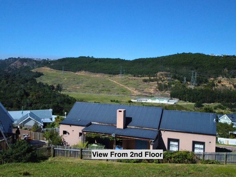 Elevated view overlooking the residential property, surrounding landscape, and distant hills, showcasing the roof structure and exterior grounds.