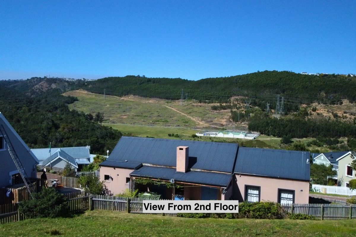 Elevated view overlooking the residential property, surrounding landscape, and distant hills, showcasing the roof structure and exterior grounds.