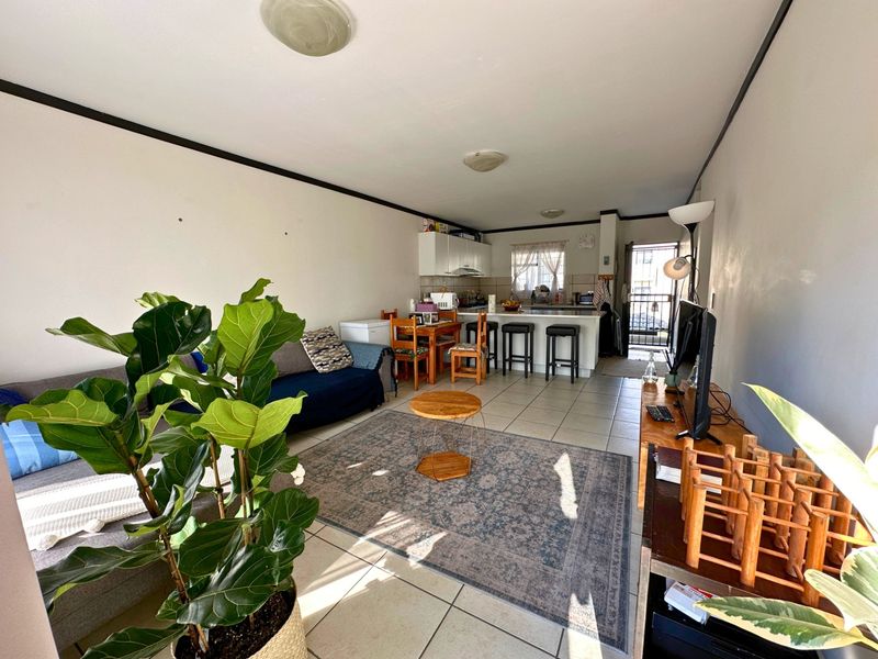 Open plan living and kitchen area featuring tiled flooring and a functional kitchen layout with a breakfast counter.