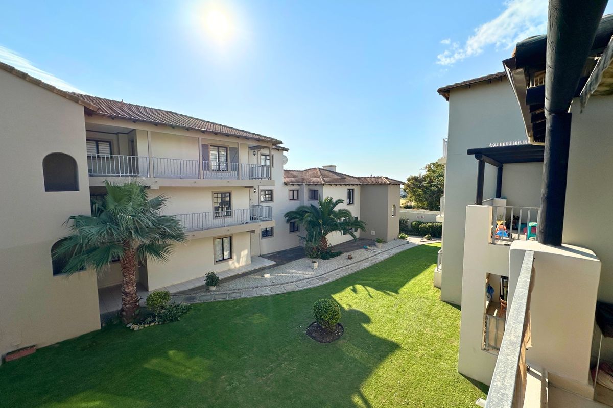 A view of the apartment complex courtyard featuring a well-maintained lawn, paved pathways, and multiple levels of balconies.