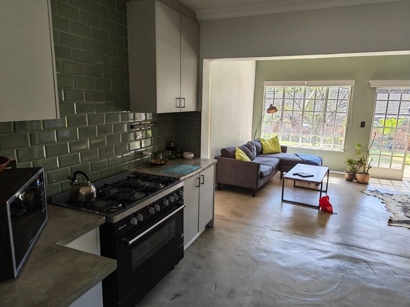 Open-plan kitchen and living area featuring modern cabinetry, a gas stove, subway tile backsplash, polished concrete floors, and direct access to the garden.