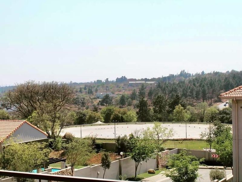 Elevated view from a balcony overlooking the surrounding neighborhood, landscaped grounds, and distant hills.