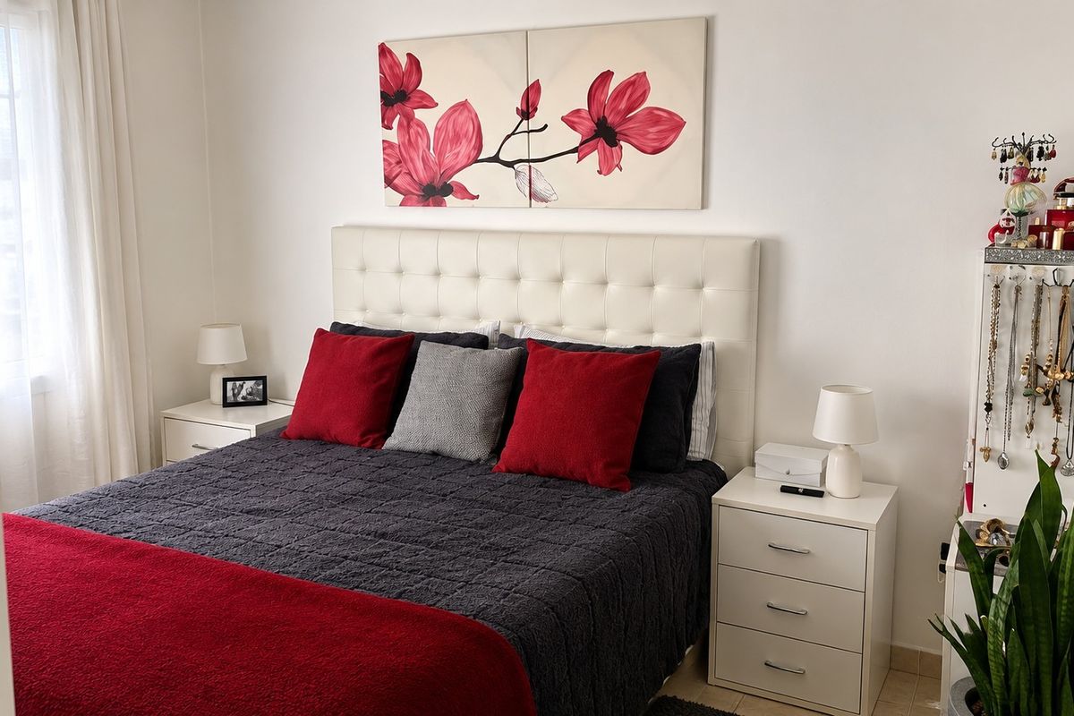 A well-maintained bedroom featuring neutral walls, tiled flooring, and a bright window with sheer curtains.