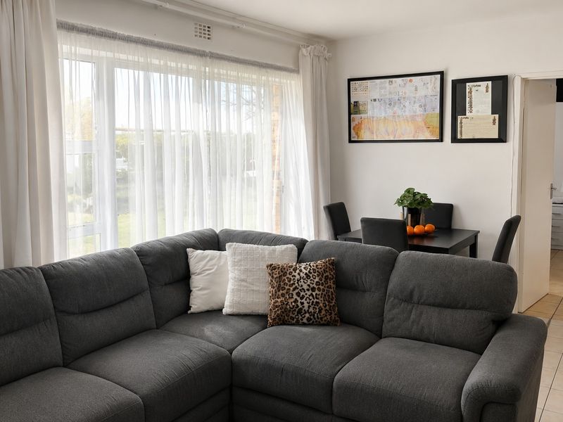 Open plan living and dining area featuring large windows, neutral walls, and tiled flooring, providing a bright and functional space.