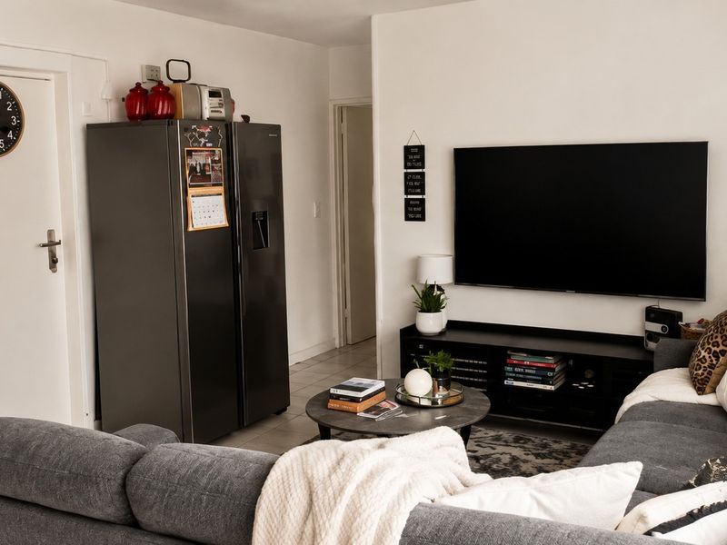 An open-plan living area featuring a compact kitchen with built-in cabinetry and a comfortable lounge space with wall-mounted television.