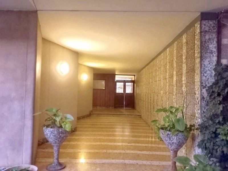 A spacious commercial entrance hall featuring stone-tiled flooring, textured wall cladding, and warm recessed lighting leading to a double-door entrance.