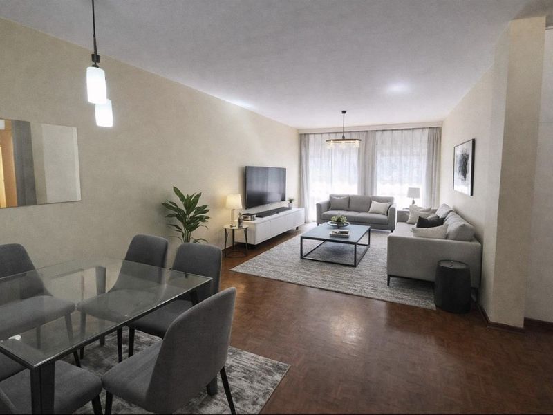 Spacious open-plan living and dining area featuring warm parquet flooring, modern pendant lighting, and large windows allowing for ample natural light.