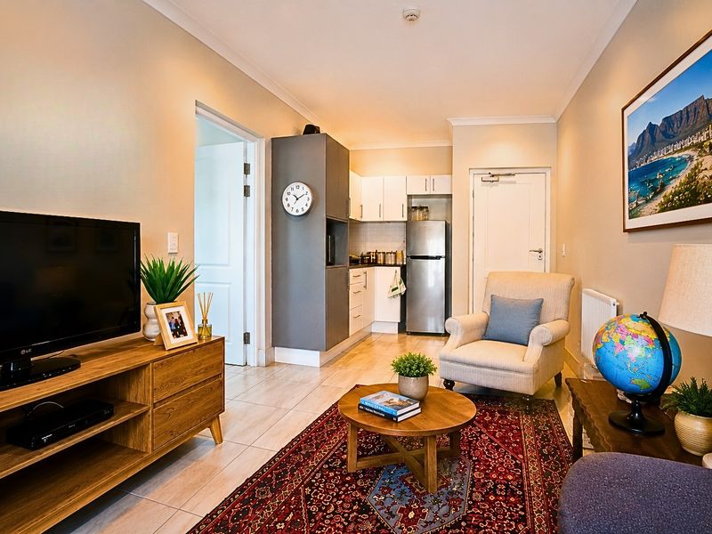 An open-plan living area featuring a compact kitchenette with built-in cabinetry and tiled flooring, creating a functional and comfortable retirement living space.