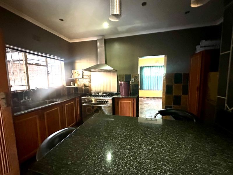 A functional kitchen featuring granite countertops, wooden cabinetry, and a stainless steel gas stove with an extractor fan.
