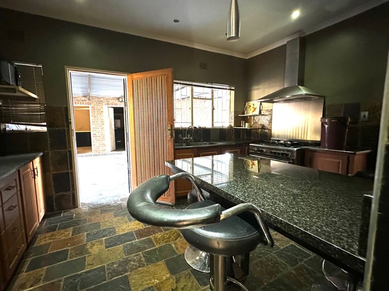 Kitchen featuring granite countertops, a gas stove with stainless steel extractor, and slate flooring, with direct access to an outdoor patio area.