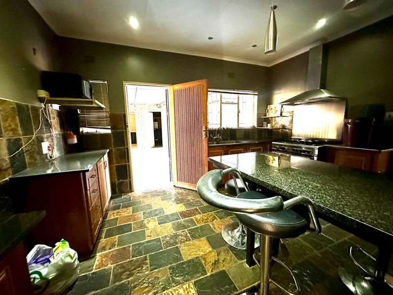 A functional kitchen featuring granite countertops, a built-in stove with extractor fan, and durable slate tile flooring throughout the workspace.