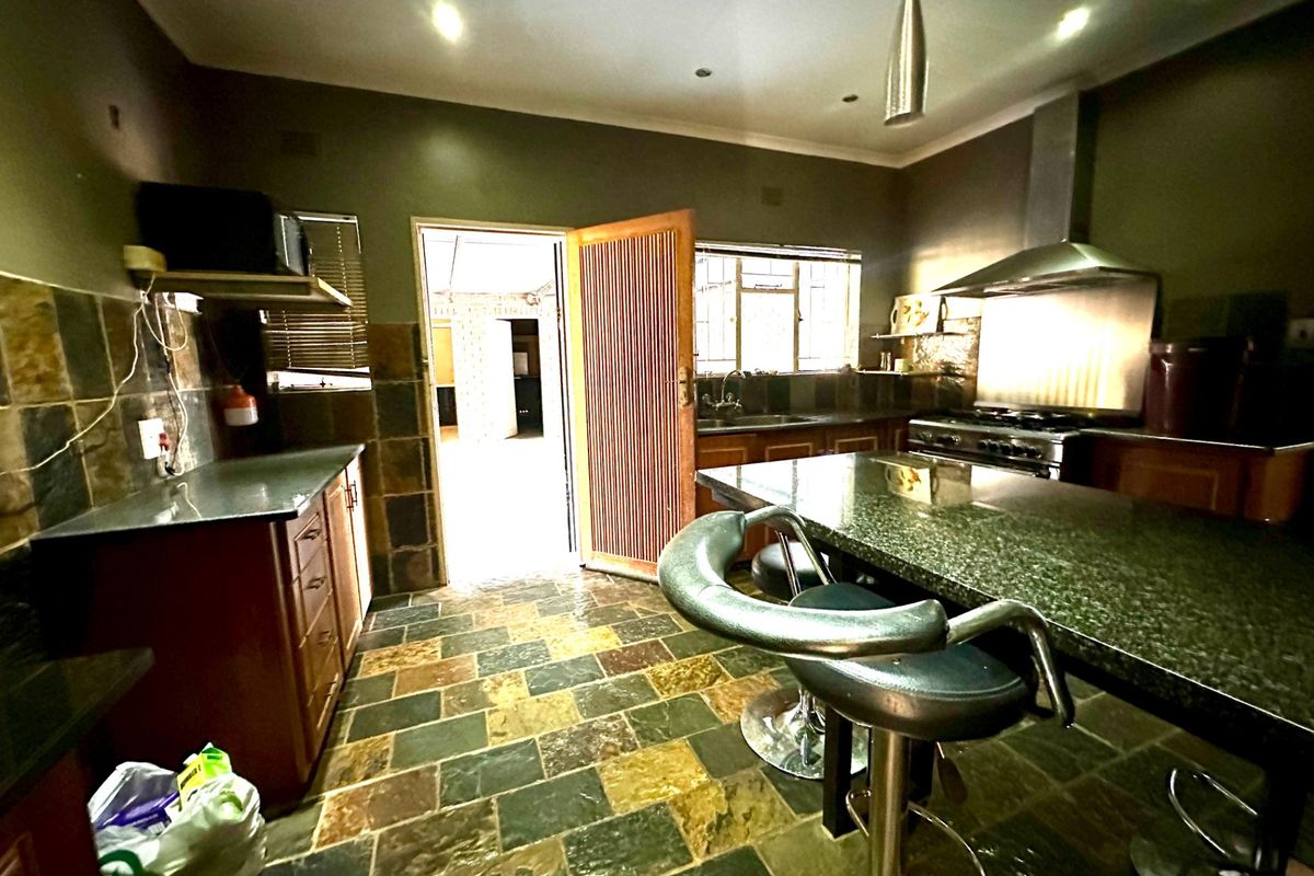 A functional kitchen featuring granite countertops, a built-in stove with extractor fan, and durable slate tile flooring throughout the workspace.