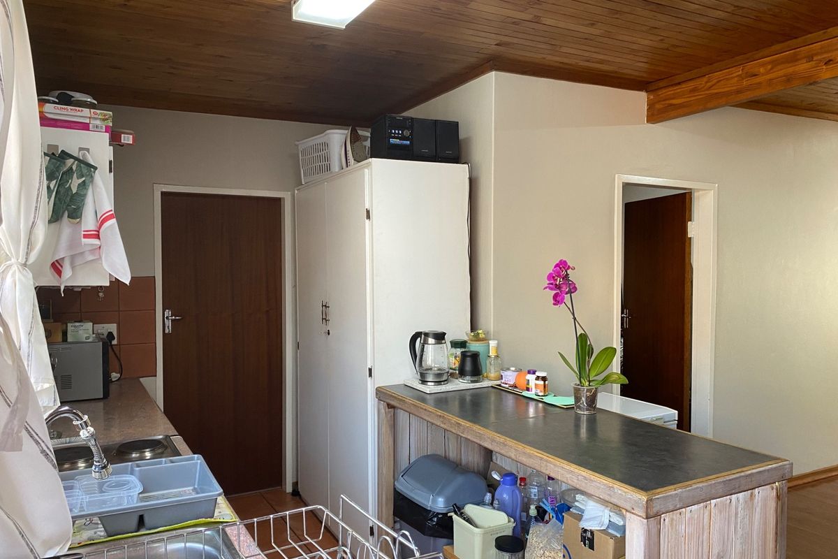 A functional kitchen area featuring wooden ceilings, built-in cabinetry, and a breakfast bar, offering potential for modernization and aesthetic updates.