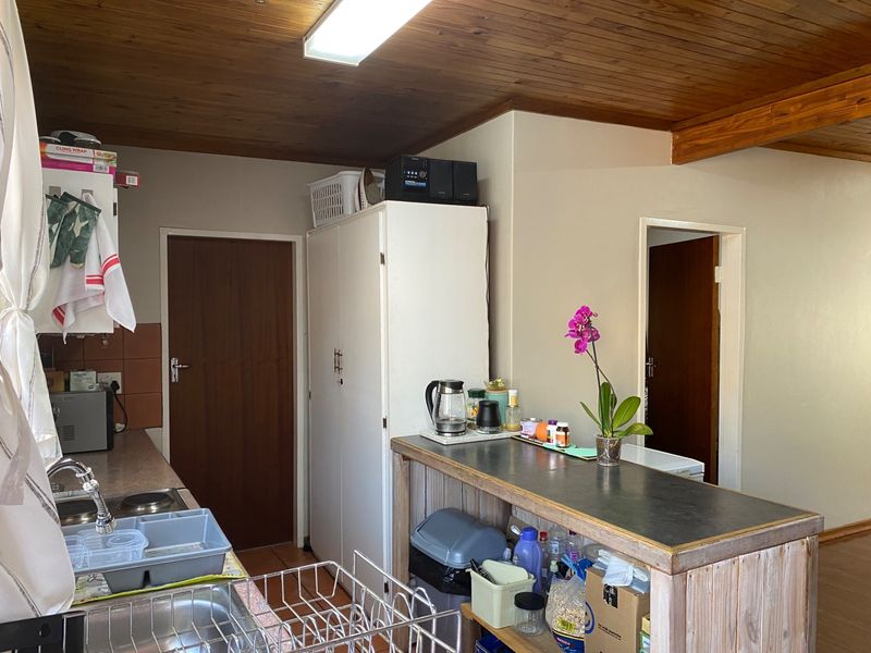 A functional kitchen area featuring wooden ceilings, built-in cabinetry, and a breakfast bar, offering potential for modernization and aesthetic updates.