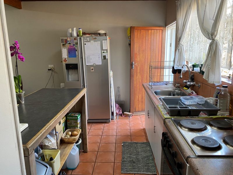 A functional kitchen featuring tiled flooring, a built-in stove, and a double sink, offering a practical layout with potential for modern updates.