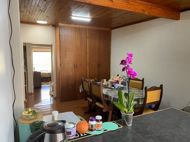 Open plan living and dining area featuring timber ceiling, laminate flooring, and extensive built-in wooden cabinetry.