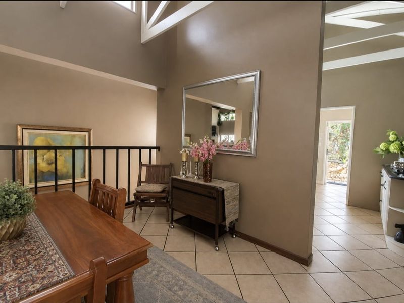 Open plan living area featuring high vaulted ceilings with exposed beams, tiled flooring, and a metal balustrade overlooking the lower level.
