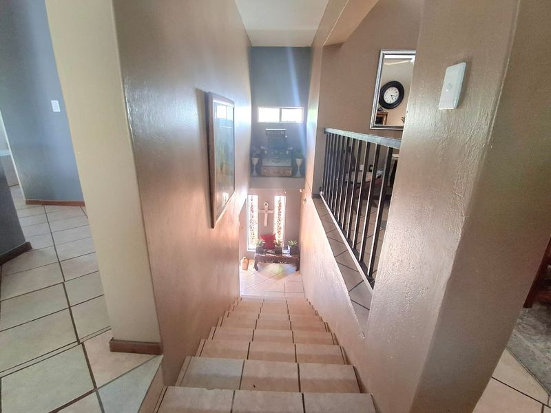 A view looking down a tiled staircase featuring a metal balustrade and neutral wall finishes, connecting different levels of the home.