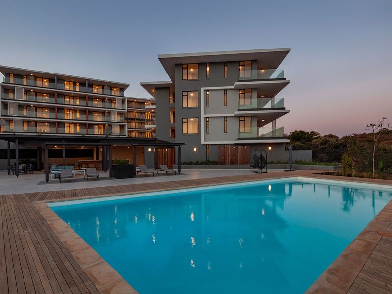 Modern apartment complex featuring a large swimming pool, timber decking, and covered outdoor patio area with contemporary architectural design.