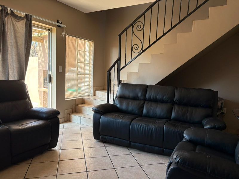 Living room featuring tiled flooring, a wrought iron staircase railing, and a sliding glass door providing access to the outdoor area.