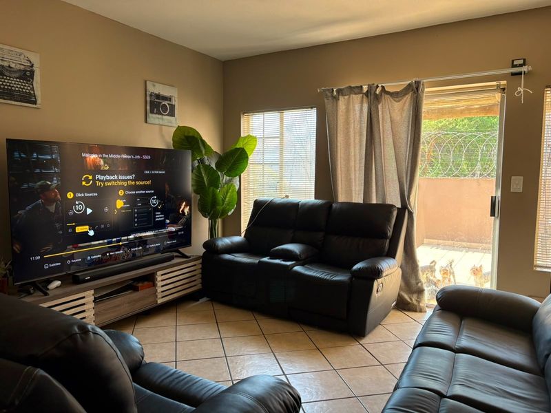 A comfortable living room featuring tiled flooring and a sliding glass door that provides access to the outdoor area.