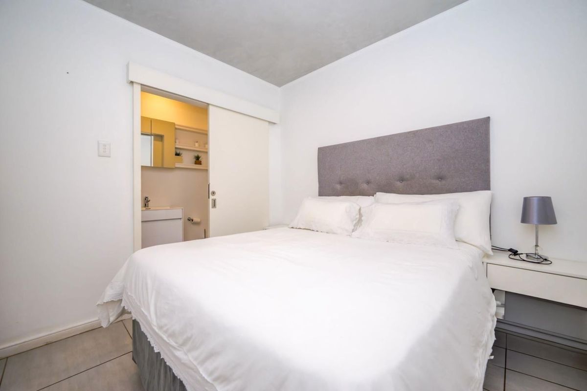 A well-maintained bedroom featuring tiled flooring and a convenient sliding door providing direct access to an en-suite bathroom.