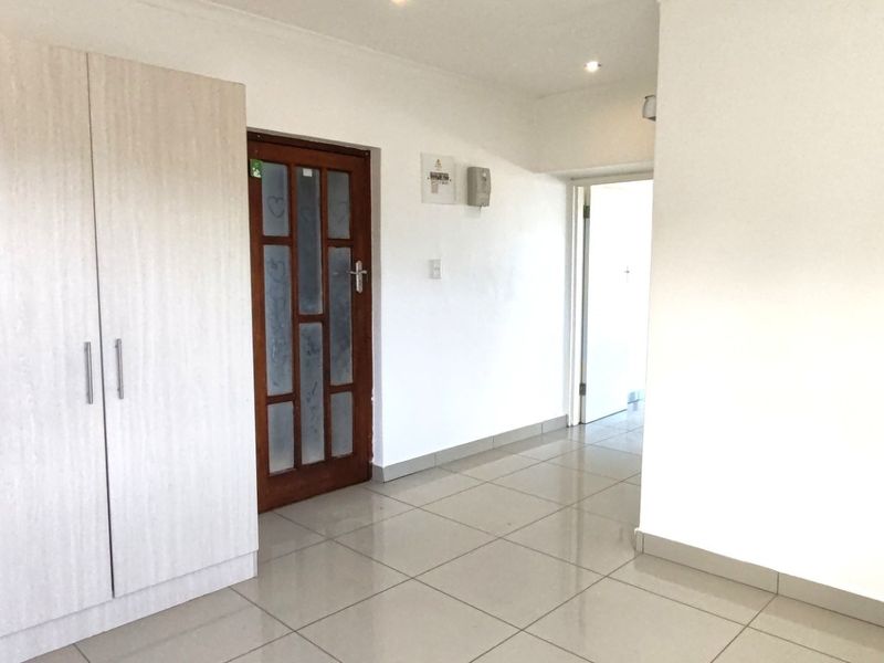 A bright, tiled hallway featuring a built-in wardrobe and recessed lighting, providing a clean and functional transition space within the apartment.