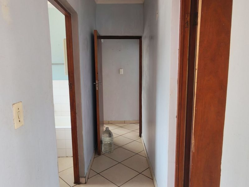 A functional hallway featuring tiled flooring and wooden door frames, providing access to adjacent rooms within the apartment.