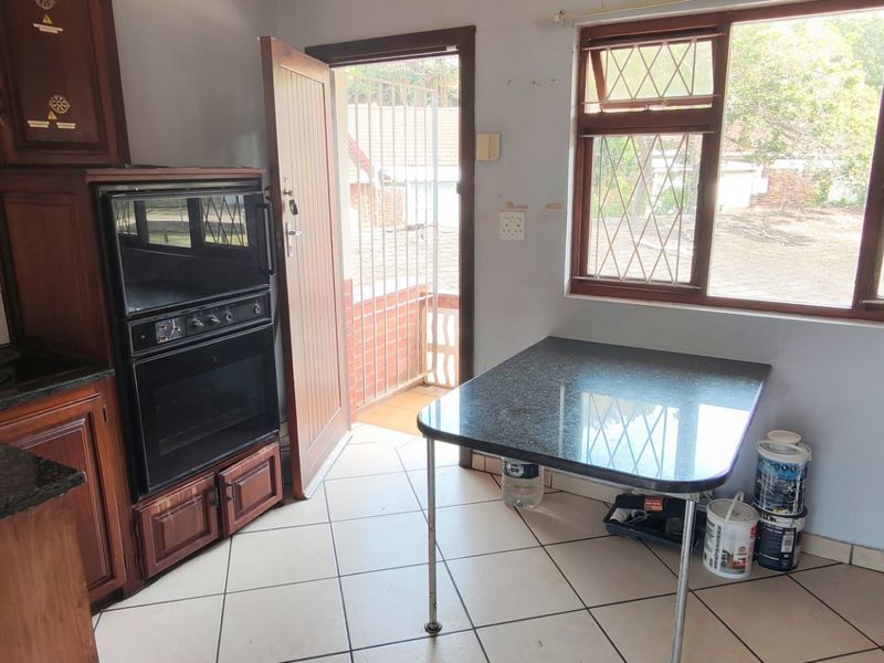 A dated kitchen featuring wooden cabinetry, granite countertops, and a built-in double oven, with direct access to an outdoor area.