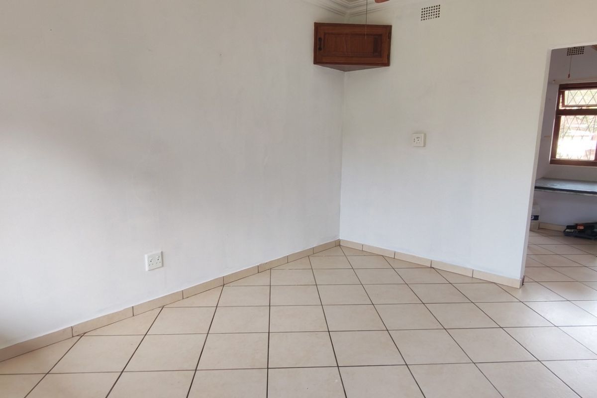 An empty living area featuring ceramic floor tiles, a corner wall cabinet, and neutral white walls, providing a blank canvas for interior design.