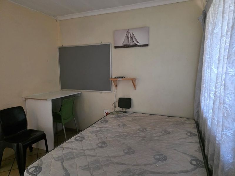A compact bedroom featuring tiled flooring and neutral wall finishes, suitable for a single bed setup.