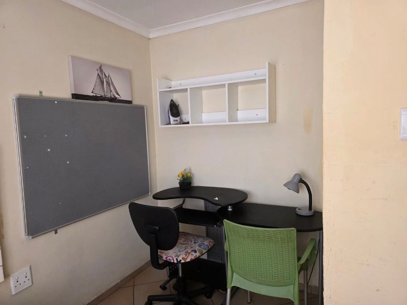 A compact home office space featuring built-in wall shelving and tiled flooring, suitable for a dedicated workspace or study area.