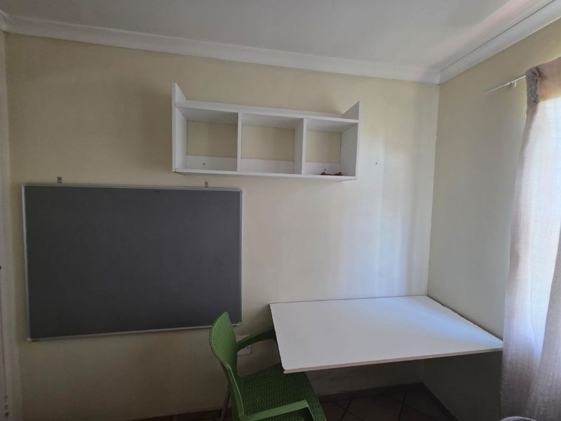 A functional home office space featuring a wall-mounted desk, built-in shelving, and tiled flooring, providing a compact area for work or study.