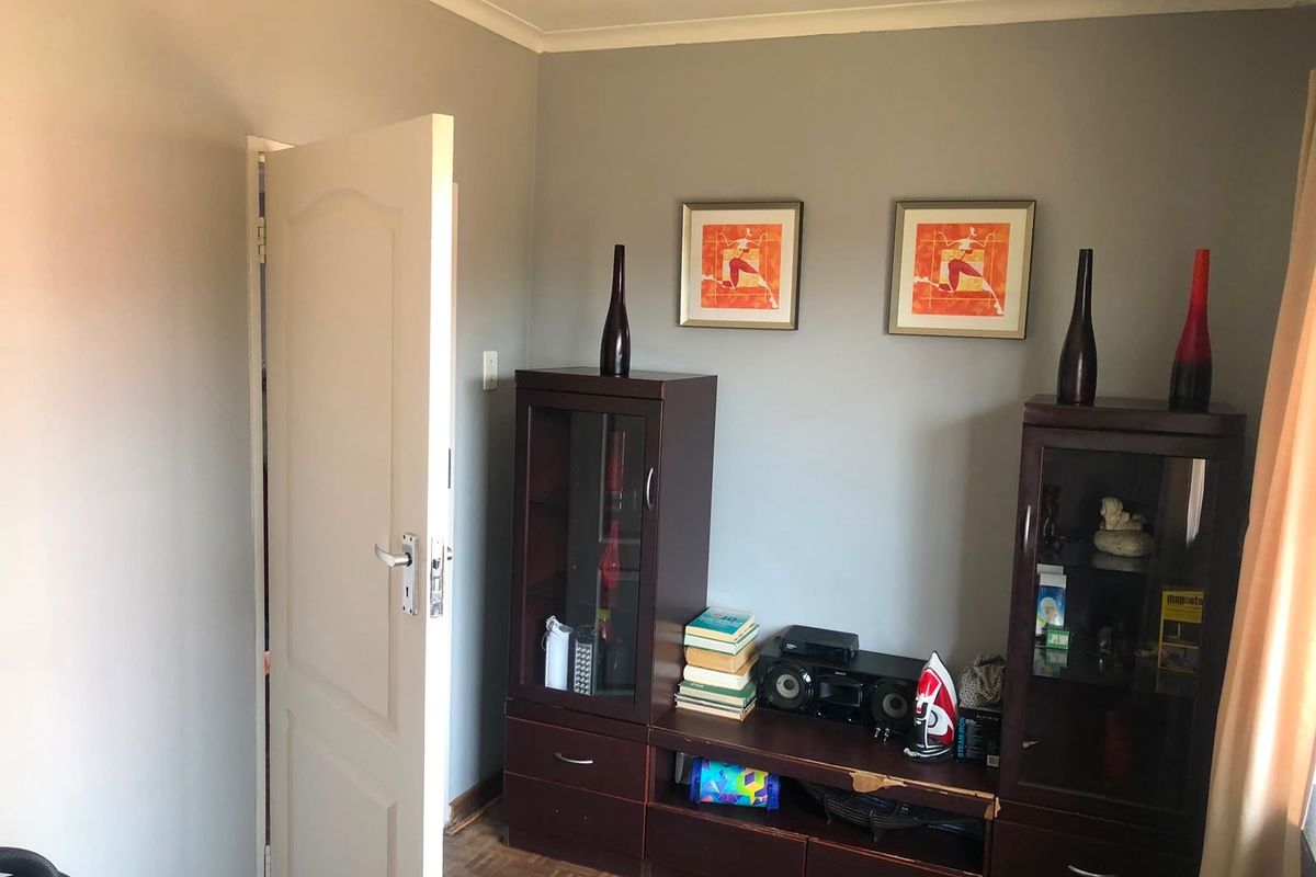 A bedroom featuring parquet flooring and coved ceilings, currently utilized with storage cabinetry.
