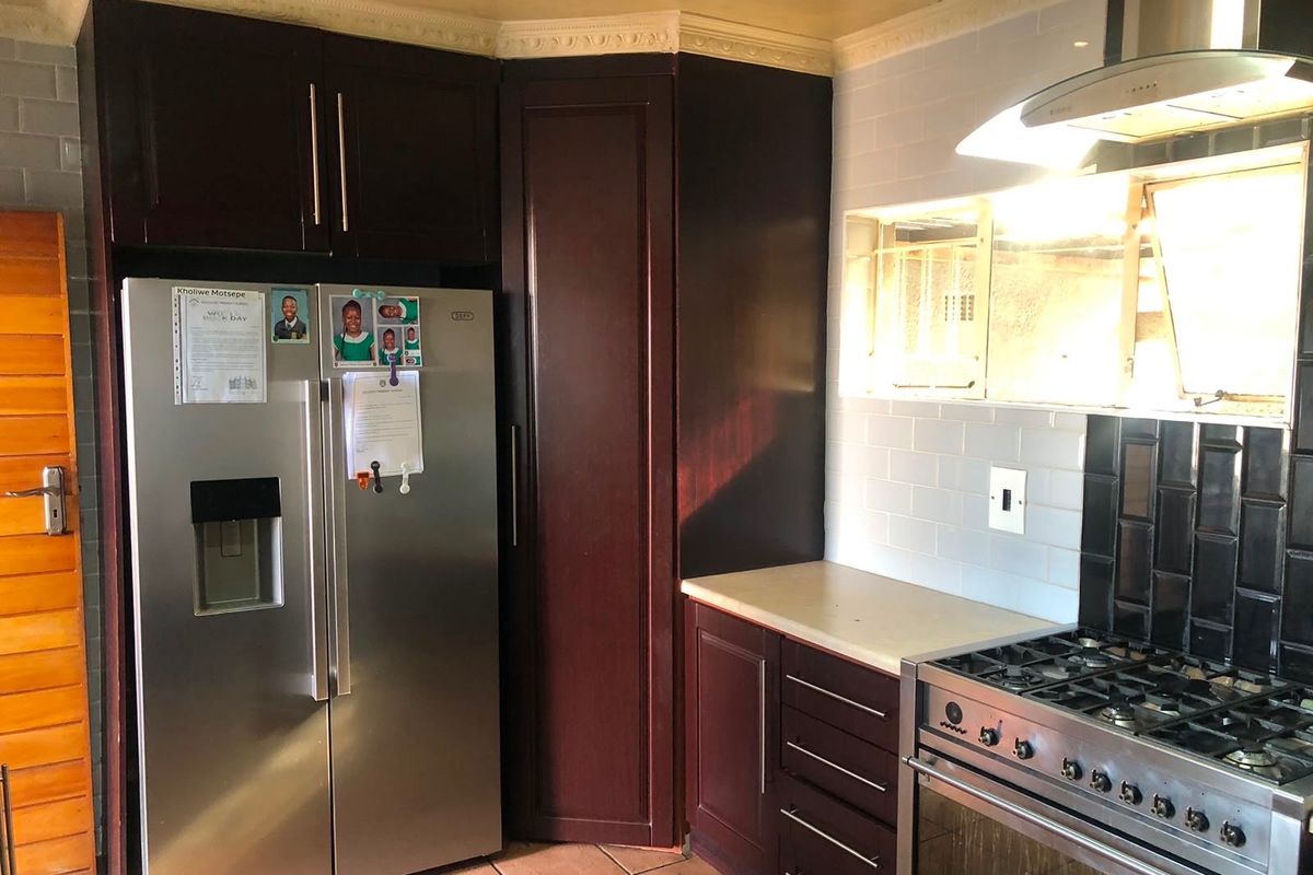 A functional kitchen featuring dark wood cabinetry, a subway tile backsplash, and a stainless steel gas stove with an integrated extractor fan.