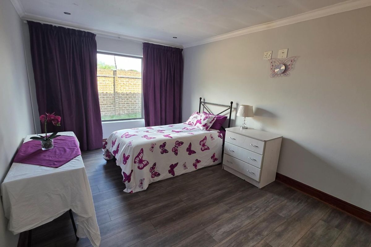 A well-maintained bedroom featuring modern laminate flooring, neutral wall tones, and recessed ceiling lighting, offering a clean and functional living space.