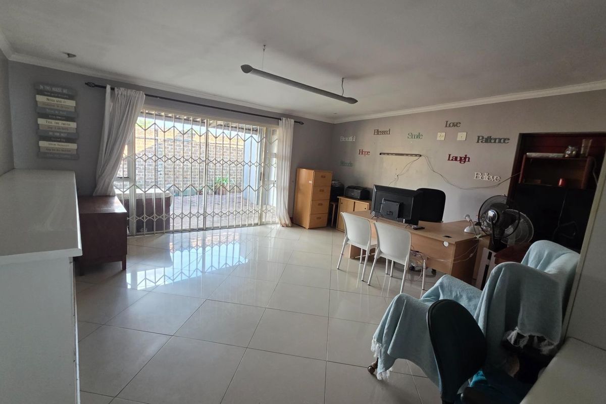 Spacious living area featuring large format floor tiles and a sliding glass door with security gate providing access to the outdoor patio.