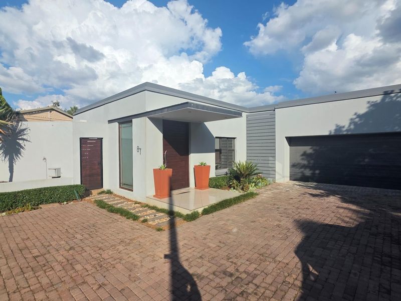 Modern single-story residence featuring a paved driveway, double garage, and a covered entrance with contemporary architectural lines.