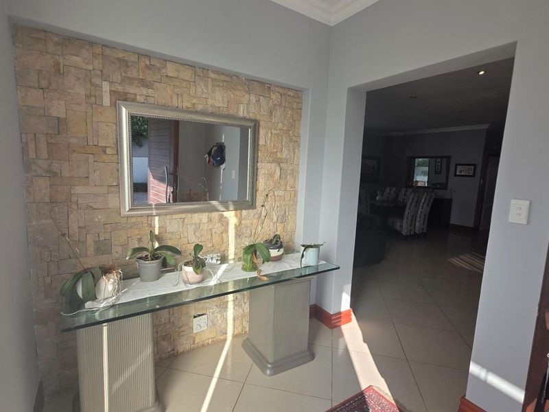 Welcoming entrance hall featuring a textured stone cladding feature wall and neutral tiled flooring, leading into the main living areas.