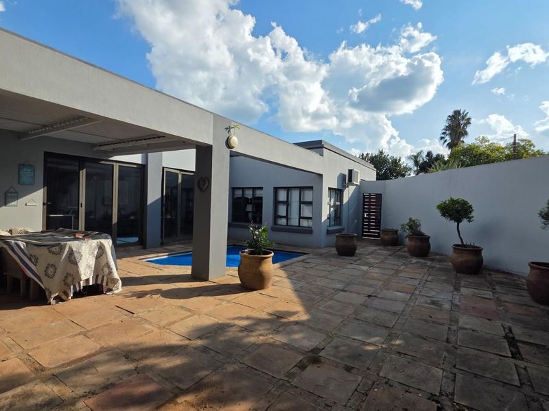 Spacious covered patio area featuring paved flooring and direct access to a swimming pool, ideal for outdoor entertaining.