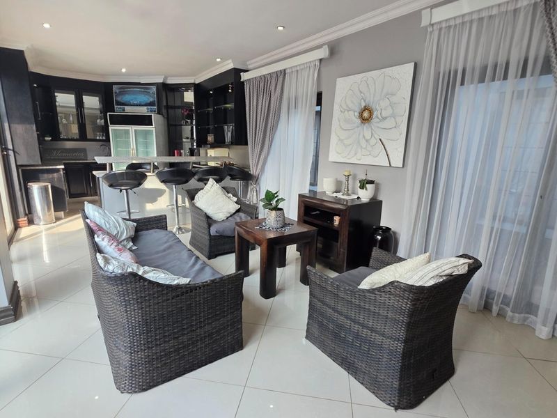 An open-plan living and kitchen area featuring modern dark cabinetry, a breakfast bar, tiled floors, and large sliding doors providing natural light.